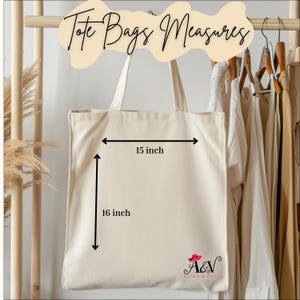 Peut inclure: Sac fourre-tout cr&egrave;me, mesurant 38 cm de large et 41 cm de haut. Il pr&eacute;sente un design simple avec un logo dans le coin inf&eacute;rieur droit. Le texte "Tote Bags Measures" est en haut. Le sac est suspendu.