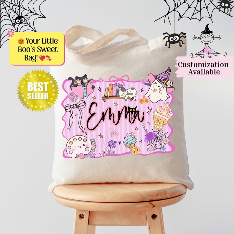Peut inclure: Un sac fourre-tout en toile beige avec un motif sur le th&egrave;me d'Halloween. Le motif comprend un cadre rose avec le nom "Emma", ainsi que des illustrations de chat, fant&ocirc;me, bonbons et araign&eacute;es. Le texte sur le sac indique "Your Little Boo's Sweet Bag!" et "Best Seller".