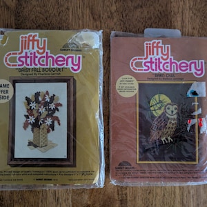 May include: Two vintage Jiffy Stitchery kits. One features a "Daisy Fall Bouquet" design, the other a "Barn Owl" design. Both kits are in their original packaging, with the brand name in pink and orange.