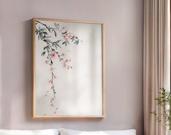 Könnte beinhalten: Ein weißes Sofa mit braunen Kissen und einer weißen Decke. Ein gerahmtes Bild mit einem Zweig rosa Blüten hängt an der Wand über dem Sofa. Ein kleiner Holztisch mit einem geflochtenen Korb steht vor dem Sofa.