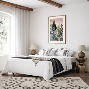 Pu&ograve; includere: Un letto bianco con una coperta nera e cuscini bianchi. Il letto si trova in una camera da letto con una grande finestra e una stampa incorniciata di un giardino di cactus sul muro. Ci sono due lampade su comodini su entrambi i lati del letto.