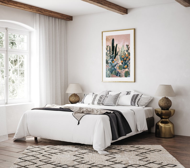 Pu&ograve; includere: Un letto bianco con una coperta nera e cuscini bianchi. Il letto si trova in una camera da letto con una grande finestra e una stampa incorniciata di un giardino di cactus sul muro. Ci sono due lampade su comodini su entrambi i lati del letto.