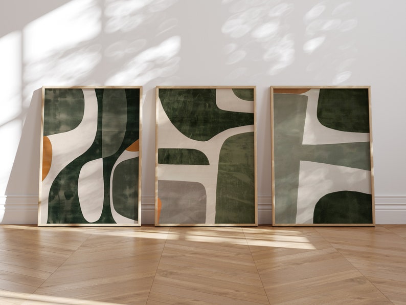 Op de afbeelding: Drie ingelijste abstracte kunstprints met een groen, wit en oranje kleurenschema. De prints tonen organische vormen en texturen.