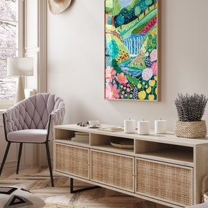 May include: A light wood media console with three woven rattan doors and open shelves. The console is decorated with a vase of lavender, three white candles, and a small plate with a few items on it. A painting of a colorful landscape with a waterfall is hanging on the wall above the console.
