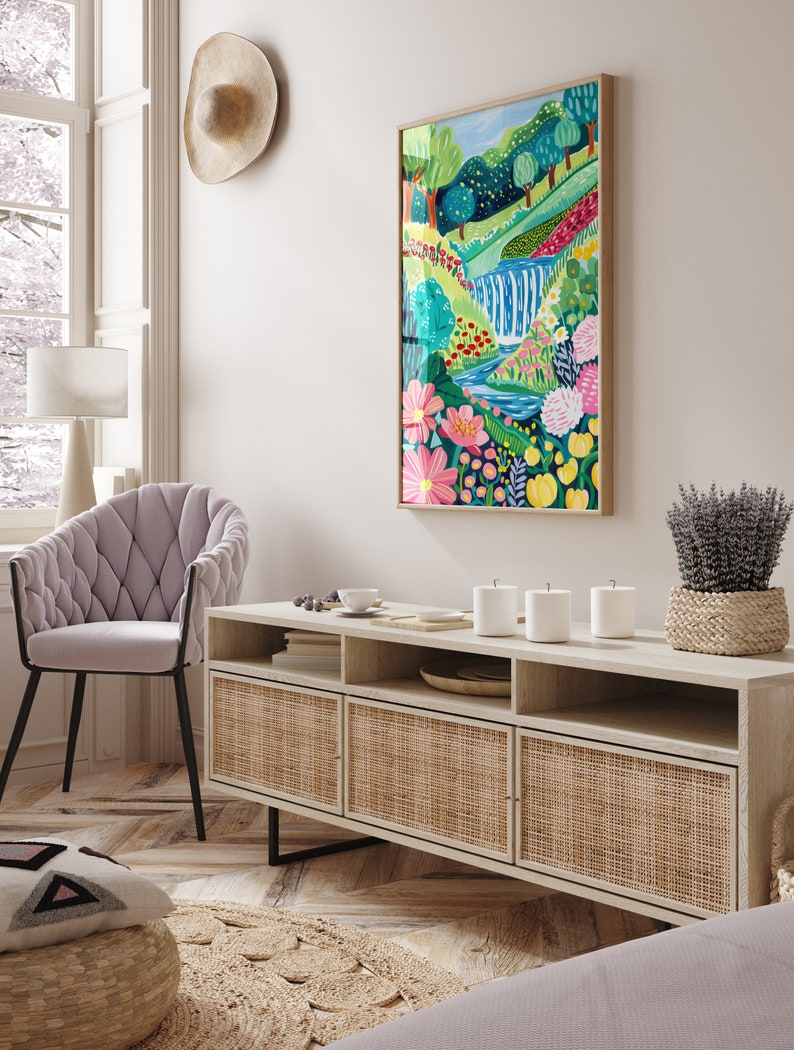 May include: A light wood media console with three woven rattan doors and open shelves. The console is decorated with a vase of lavender, three white candles, and a small plate with a few items on it. A painting of a colorful landscape with a waterfall is hanging on the wall above the console.