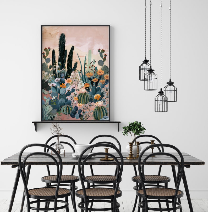 Pu&ograve; includere: Una stampa incorniciata di un paesaggio desertico con cactus e fiori in tonalit&agrave; di verde, blu e rosa. La stampa &egrave; posizionata contro un muro bianco e uno scaffale nero.