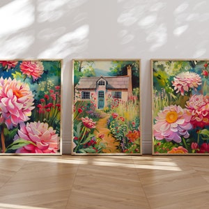 Puede incluir: Tres impresiones de arte enmarcadas que representan una cabaña rodeada de un exuberante jardín con flores rosas vibrantes. Las impresiones están dispuestas en fila sobre un suelo de madera clara.