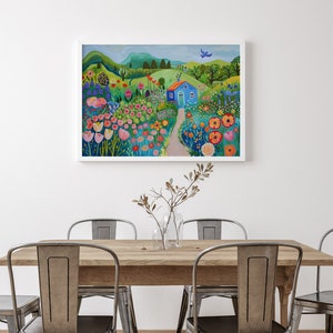 May include: A painting of a blue house with a green roof in a field of colorful flowers. The house is surrounded by green trees and hills. A blue bird flies overhead.