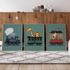 以下が含まれることがあります： 青緑色の背景に、漫画の動物が列車に乗っている様子を描いた額装されたプリントが3枚。最初のプリントは、蒸気雲が上にある列車を運転するゾウを描いています。2枚目は、列車に乗るキリンとライオンを描いています。3枚目は、列車の屋根に鳥が乗っている列車に乗るシマウマを描いています。