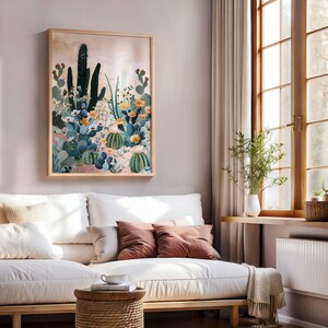Pu&ograve; includere: Una stampa incorniciata di un paesaggio desertico con cactus e fiori in tonalit&agrave; di verde, giallo e rosa. La stampa &egrave; posizionata contro un muro rosa chiaro e un divano bianco con cuscini.