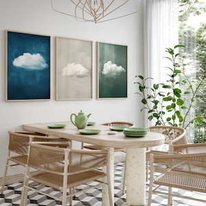 Puede incluir: Un comedor con una pared blanca y una mesa de madera con seis sillas. Hay tres impresiones enmarcadas en la pared con un diseño de nube en diferentes colores. Una tetera verde y cuatro platos están sobre la mesa.