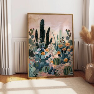 Pu&ograve; includere: Un'illustrazione incorniciata di un paesaggio desertico con cactus, piante grasse e fiori in tonalit&agrave; di verde, rosa e giallo. Lo sfondo &egrave; di un rosa tenue.