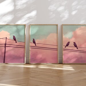 May include: Three framed prints with a pastel pink and blue sky background. Each print features a silhouette of two birds perched on a wire.