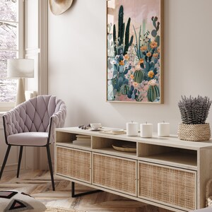 Pu&ograve; includere: Una consolle multimediale in legno chiaro con tre ante in rattan intrecciato e ripiani aperti. La consolle &egrave; decorata con tre candele bianche, una piccola ciotola bianca e un vassoio intrecciato. Una grande stampa incorniciata di un paesaggio desertico con cactus e fiori &egrave; appesa al muro dietro la consolle.