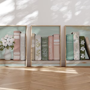 May include: Three framed prints of vintage books on a shelf. The first print features a bouquet of white flowers in a vase. The second print features a row of books in shades of pink, green, and cream. The third print features a row of books in shades of green and cream.