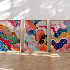 May include: Three framed abstract paintings with colorful, organic shapes and patterns. The paintings are in a modern style and feature a variety of colors, including pink, blue, green, yellow, and orange.