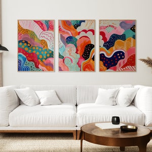 May include: Three abstract paintings with colorful, swirling patterns in shades of pink, blue, green, yellow, orange, and white. The paintings are framed in natural wood.