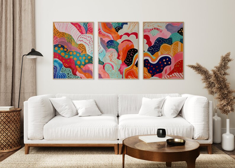 May include: Three abstract paintings with colorful, swirling patterns in shades of pink, blue, green, yellow, orange, and white. The paintings are framed in natural wood.