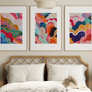 May include: Three framed abstract paintings with colorful, organic shapes and patterns. The paintings are in a modern style and feature a variety of colors, including pink, blue, green, yellow, and orange.