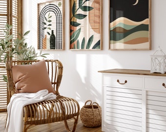 May include: Three abstract art prints in wooden frames hang on a white wall above a white dresser with a wooden top. The prints feature geometric shapes, leaves, and a crescent moon. A wicker chair with a brown cushion sits in front of the dresser.