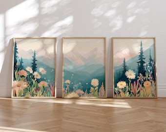May include: Three framed prints of a watercolor painting of a mountain range with wildflowers in the foreground. The mountains are painted in shades of blue and green, and the wildflowers are in shades of pink, white, and yellow.