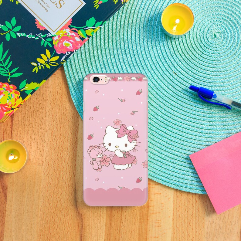 K&ouml;nnte beinhalten: Eine rosa iPhone-H&uuml;lle mit einem Hello-Kitty-Design. Hello Kitty tr&auml;gt ein rosa Kleid und eine wei&szlig;e Schleife. Sie h&auml;lt einen rosa Teddyb&auml;r. Der Hintergrund ist rosa mit wei&szlig;en Punkten und wei&szlig;en Blumen.