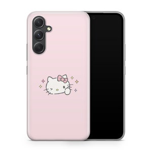 May include: A pink phone case with a white Hello Kitty character with a pink bow and sparkling stars. The case is designed for a phone with a triple camera lens.