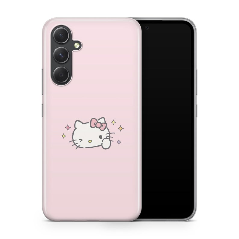 May include: A pink phone case with a white Hello Kitty character with a pink bow and sparkling stars. The case is designed for a phone with a triple camera lens.