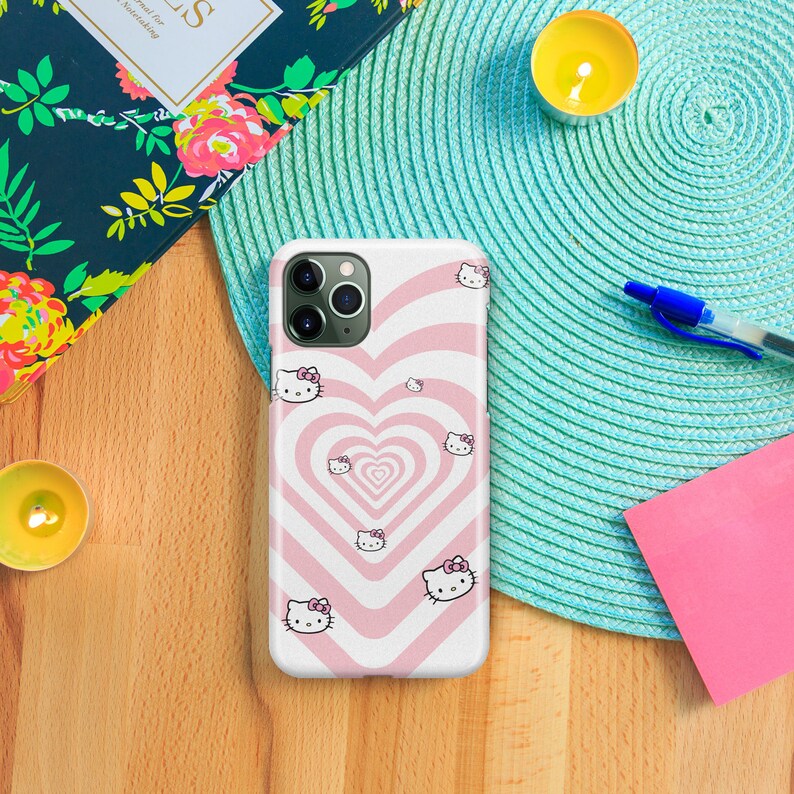 May include: A pink and white phone case with a repeating pattern of hearts and Hello Kitty characters. The case is designed for an iPhone.