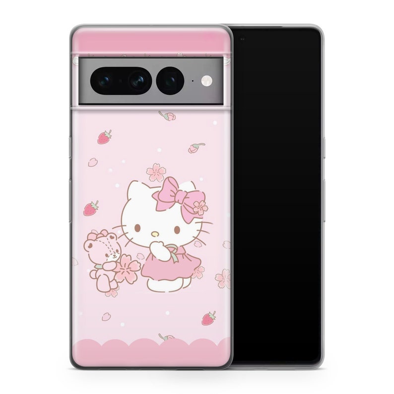 May include: A pink phone case with a Hello Kitty design. Hello Kitty is wearing a pink dress and holding a teddy bear. The case has a pink background with white flowers and strawberries.
