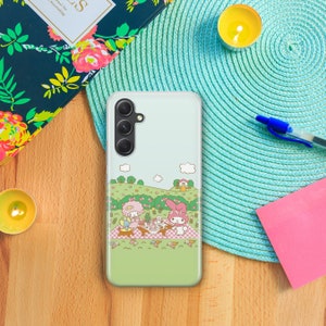 May include: A clear phone case with a green background featuring a picnic scene with two cartoon characters, My Melody and Little Twin Stars, in a field with flowers and a small house.