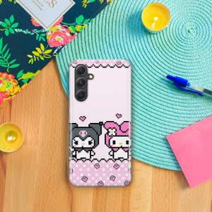 May include: A pink and white phone case with a pixelated design of Hello Kitty and My Melody. The case has a pink and white checkered pattern with pink strawberries.