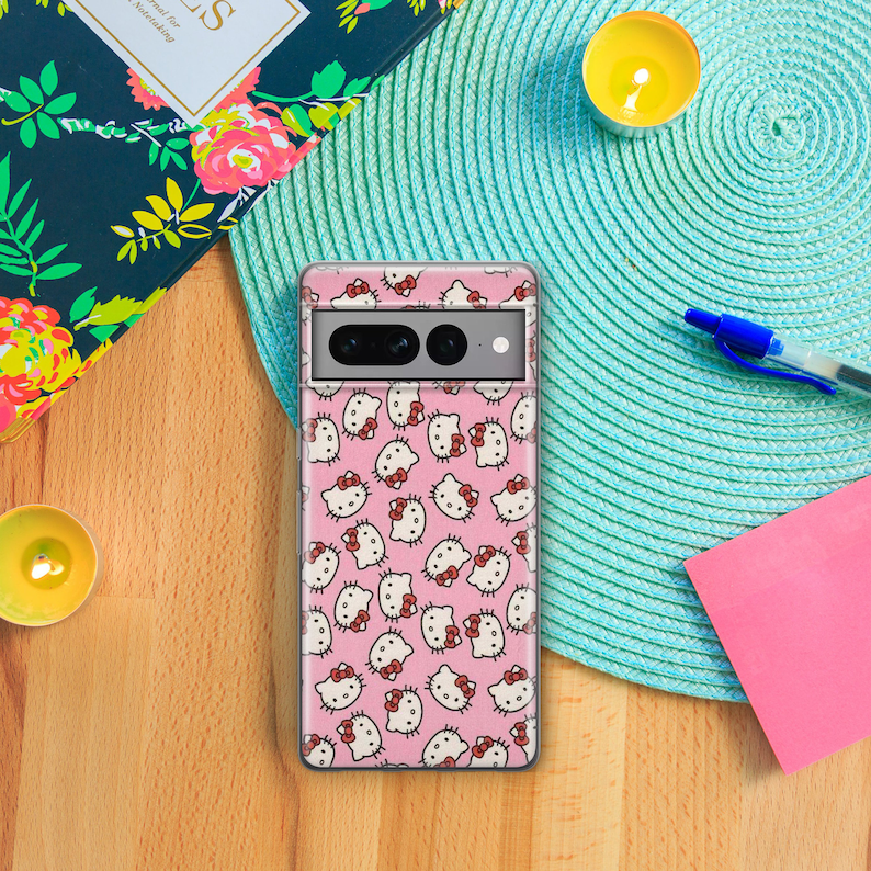 Op de afbeelding: Een transparante telefoonhoes met een roze achtergrond en een herhalend patroon van Hello Kitty-figuren. De hoes heeft een zwarte camera-uitsparing.