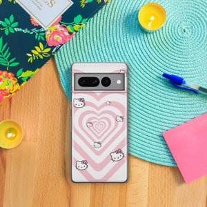 May include: A pink and white phone case with a swirling heart design and Hello Kitty characters. The case is designed for a phone with a camera bump.