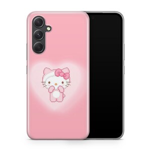 May include: A pink phone case with a white Hello Kitty character in the center. The case has a cutout for the phone's camera.