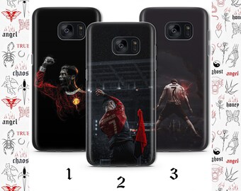 May include: Three phone cases with different designs featuring a soccer player in a red and black uniform. The player is in a stadium setting. The phone cases are black and have a clear back.