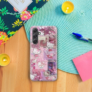 Op de afbeelding: Een transparante telefoonhoes met een roze, wit en zwart Hello Kitty-ontwerp. De hoes heeft een collage van Hello Kitty-afbeeldingen, harten en vlinders. De telefoonhoes is ontworpen voor een smartphone met een drievoudige camera lens.
