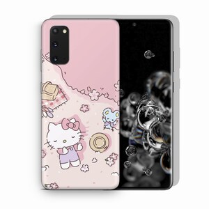 Op de afbeelding: Een roze telefoonhoesje met een Hello Kitty-ontwerp. Hello Kitty ligt op haar rug met haar armen uitgestrekt. Rechts van Hello Kitty staat een klein muisfiguurtje. De achtergrond is een roze en wit bloemenpatroon.