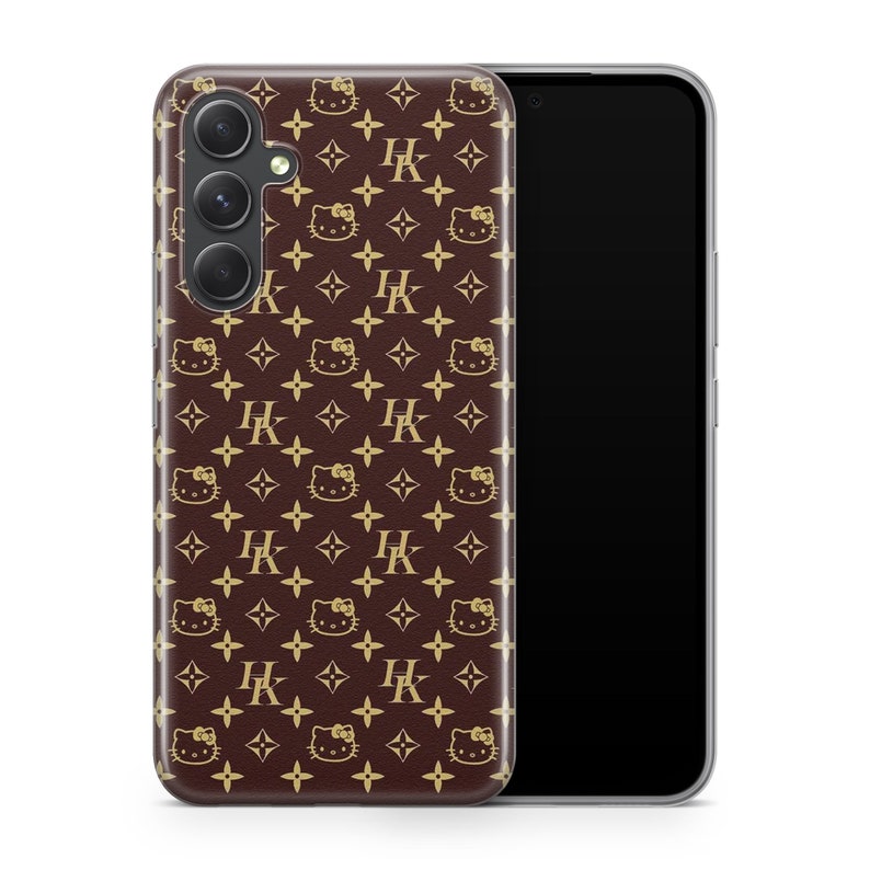 Op de afbeelding: Een bruine telefoonhoes met een gouden Hello Kitty en Louis Vuitton patroon. De hoes wordt getoond met een zwart telefoonscherm.