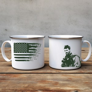 May include: Two white enamel mugs with a silver rim. One mug features a green American flag with the text "MURPH 1 MILE RUN 100 PULL UPS 200 PUSH UPS 300 SQUATS 1 MILE RUN". The other mug features a green silhouette of a man in military fatigues.