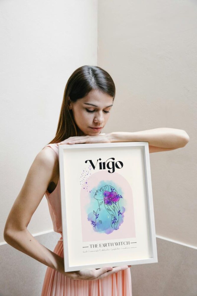 May include: A white framed print with a watercolor illustration of a Virgo zodiac sign. The illustration is in shades of blue, pink, and purple. The text "Virgo" is in black and the text "The Earth Witch" is in black below the illustration.