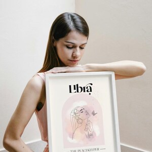 May include: A white framed print featuring a pink and white watercolour illustration of a woman with a butterfly. The text "Libra" and "The Peacekeeper" is printed in black.