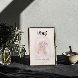 May include: A gold framed print with the word "Libra" in a stylised font. The print features a watercolour illustration of a woman with a butterfly. The text "The Peacekeeper" is below the illustration.
