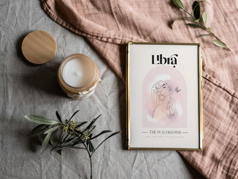 May include: A gold framed print with the word "Libra" in black text. The print features a watercolour illustration of a woman with flowers in her hair and a butterfly. The text "The Peacekeeper" is below the illustration.