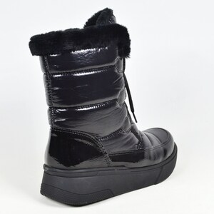 May include: Black quilted winter boots with a faux fur trim around the top of the boot. The boots have a lace-up closure and a thick platform sole.