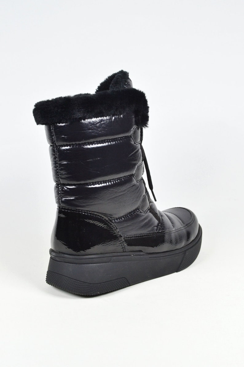May include: Black quilted winter boots with a faux fur trim around the top of the boot. The boots have a lace-up closure and a thick platform sole.