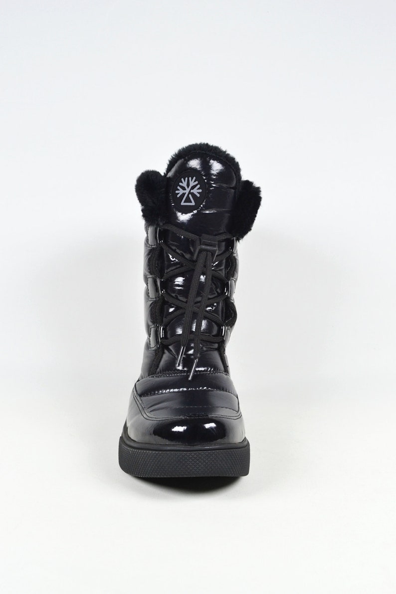 May include: Black quilted winter boots with a faux fur trim around the top and a black lace-up closure. The boots have a black logo on the side.