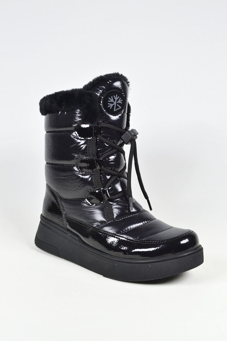 May include: Black winter boots with a faux fur lining, a lace-up front, and a chunky platform sole. The boots have a snowflake logo on the side.