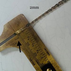 May include: Close-up of a gold chain measured with a ruler. The chain is 2 mm wide.  The ruler shows inches and millimeters.
