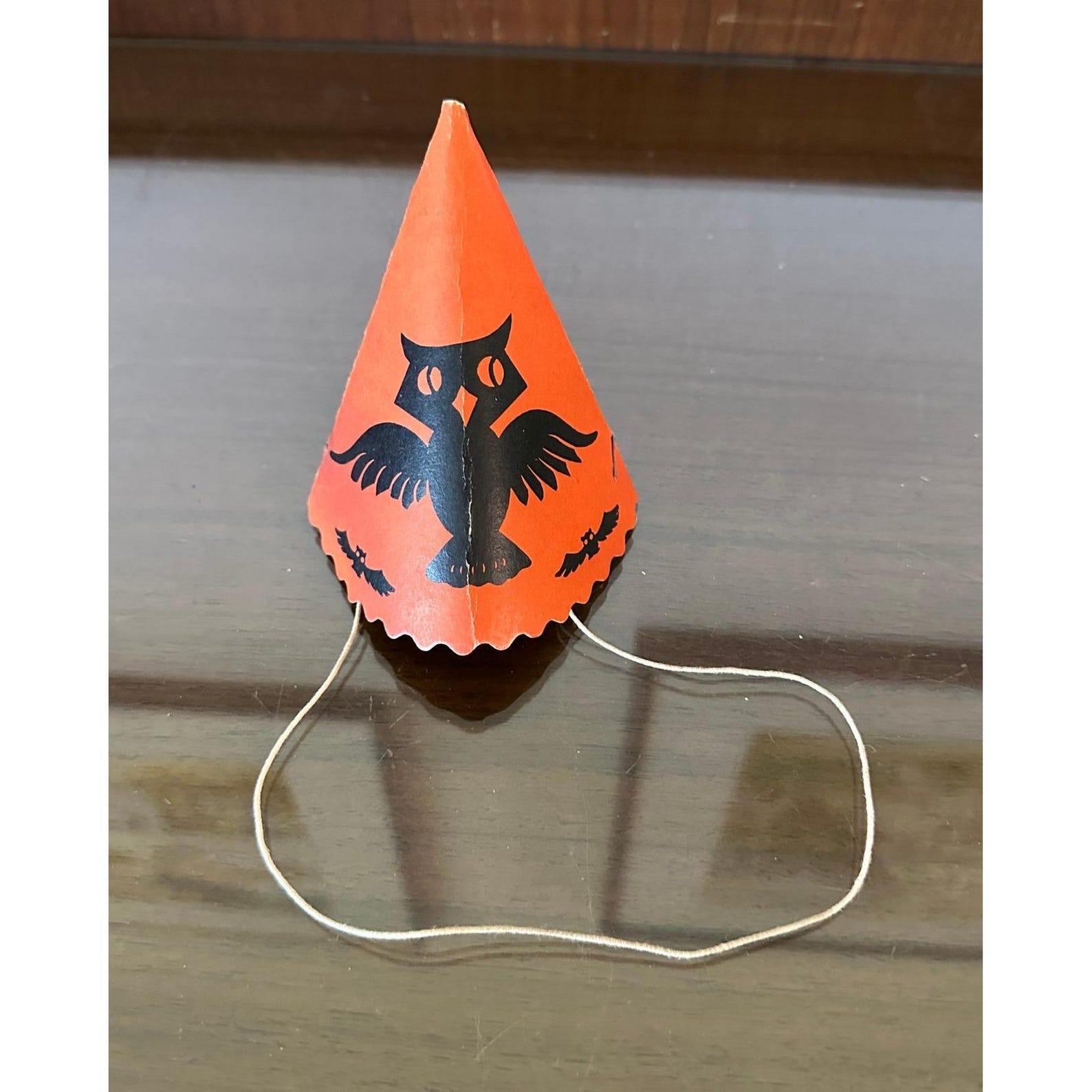 A Bold Owl Silhouette on a Cone Vintage orange cardboard party hat with a large black owl graphic.